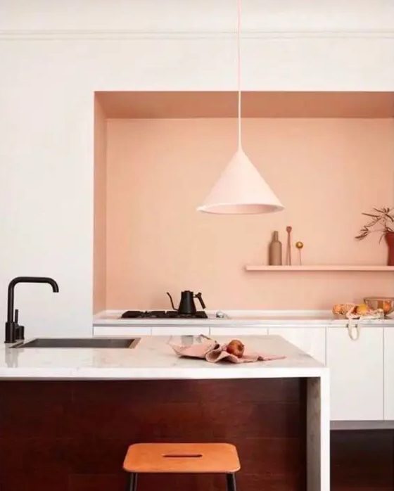 a super stylish kitchen with lower white cabinets, a textural kitchen island, a peachy pink backsplash is wow