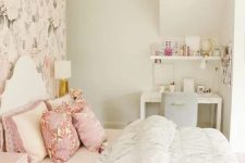 a teen girl bedroom in neutrals and pastels, with a floral accent wall, a white bed with printed and neutral bedding, a blush nightstand, a white desk and a grey chair