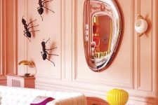 a unique living room with Peach Fuzz walls and giant ants as decor, a white tufted sofa, a mirror and some tables