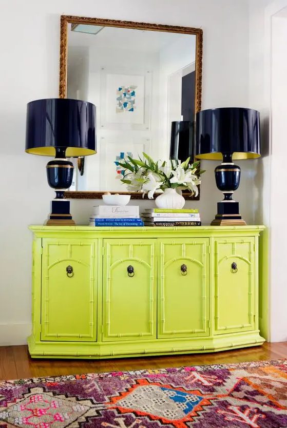 a vintage console table done in chartreuse, with navy lamps, coffee table books and blooms is a cool statement for an entryway