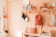 a vivacious entryway with a Peach Fuzz accent wall, a rack, a bench and some decor plus printed rugs