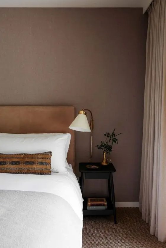 a welcoming bedroom with a brown accent wall, a bed with a leather headboard, neutral bedding, beige textiles