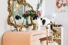 a whimsical makeup space with a Peach Fuzz vanity, a mirror in an ornated frame and a gallery wall