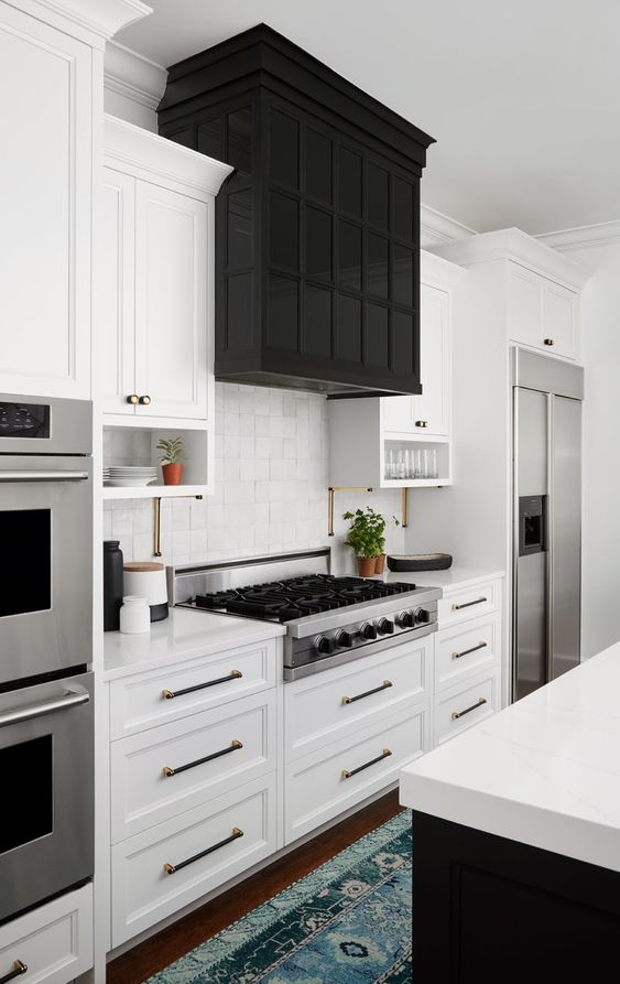 a white farmhouse kitchen with a black kitchen island and an oversized black hood with storage that echoes with the island