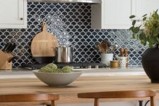 a white farmhouse kitchen with shaker cabinets, butcherblock countertops, a black fishscale tile backsplash and stools