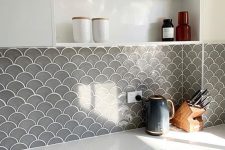 a white kitchen with a grey fish scale tile backsplash that adds color and texture to the space