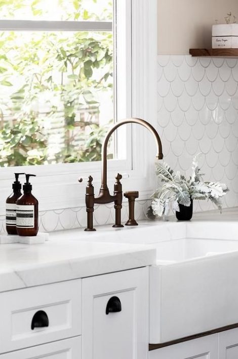 a white kitchen with black accents is made more eye-catching with a cool white fishscale tile backsplash highlighted with black grout