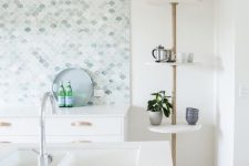 an airy white kitchen with a large aqua, white and green fish scale tile backsplash and white countertops is lovely