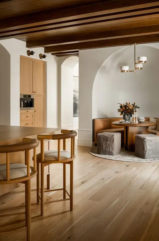 an earthy eclectic space with light and rich-stained furniture, poufs that resemble of rocks, a stained wooden ceiling