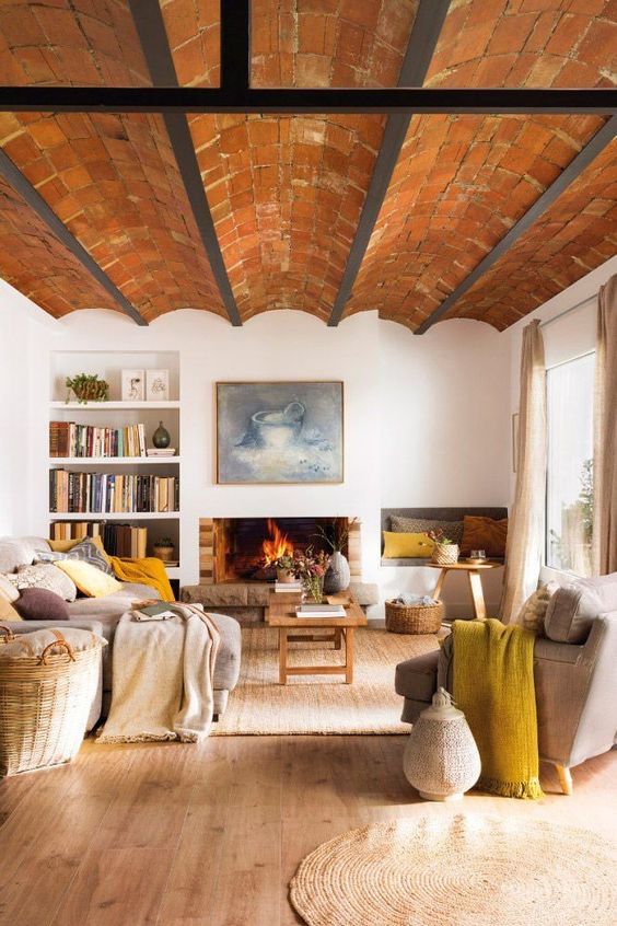 an earthy living room with a birck ceiling, a fireplace, neutral seating furniture, basket and built-in bookshelves