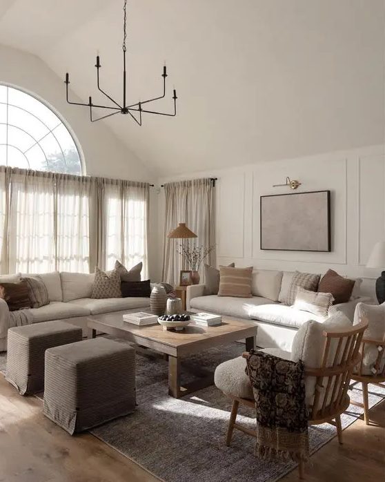 an earthy living room with creamy sofas, a low coffee table, taupe poufs, creamy chairs and printed pillows