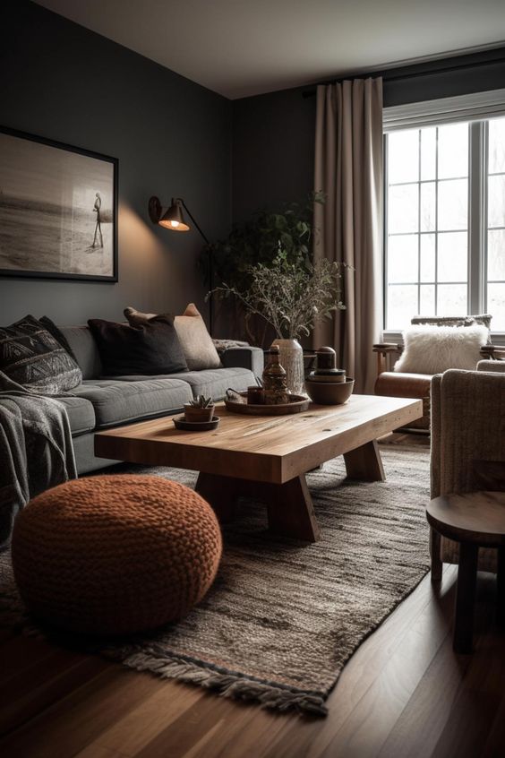 an earthy living room with grey walls, a grey sofa, a stained coffee table, leather chairs, a rust knit poufs