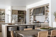 an earthy open layout with light-colored cabinets, a large metal hood, a kitchen island and grey stools and a dining zone
