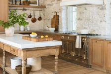 an eclectic kitchen with stone walls, light-stained cabinets, a vintage cooker and a statement hood plus a vintage kitchen island