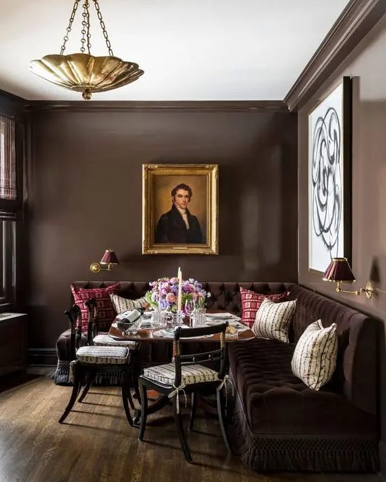 an exquisite dining room with brown walls, a large brown corner sofa, a table and chairs, some artwork
