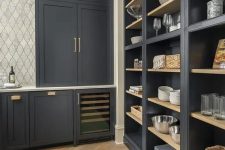 an exquisite soot pantry with built-in cabinets and shelves, gold handles and baskets plus a tiled wall is a lovely and cool space