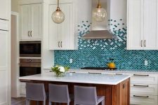 an eye-catchy kitchen with creamy shaker cabinets, a bold turquoise and green scallop tile backsplash, a stained kitchen island and taupe stools