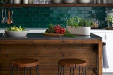 an eye-catchy kitchen with white cabinets, a bold green subway tile backsplash, open shelves, a dark-stained kitchen island and stools