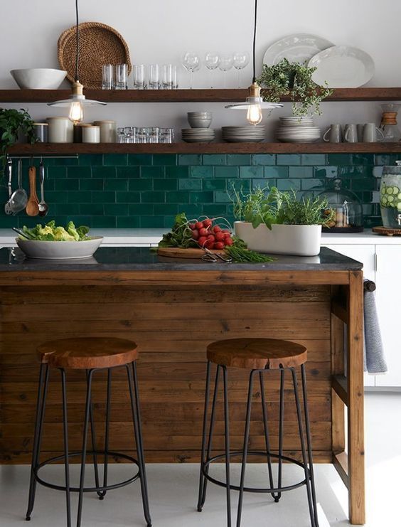 An eye catchy kitchen with white cabinets, a bold green subway tile backsplash, open shelves, a dark stained kitchen island and stools