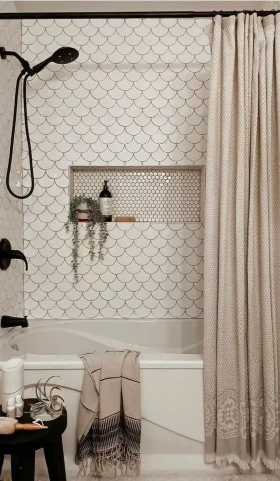 an eye-catchy neutral bathroom clad with white fihscale tiles, a niche shelf, black fixtures and neutral textiles
