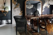 an unusual Goth dining room with soot walls and a ceiling, a living edge table, black chairs, a crystal chandelier and unique wall decor