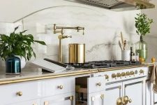 vintage glam white and gold cabinets paired with a large gold hood and a white stone countertop look amazing
