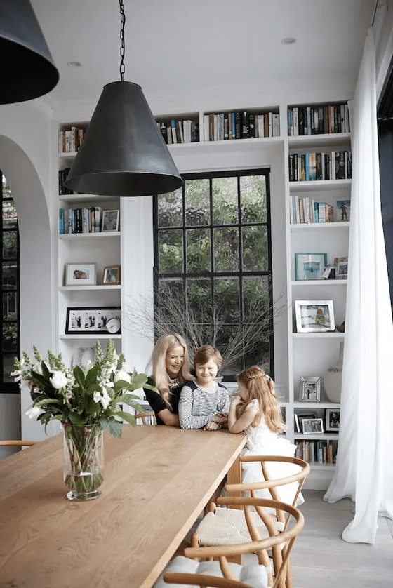 a Scandinavian dining room with built-in shelves, a wooden dining table and chairs black pendant lamps