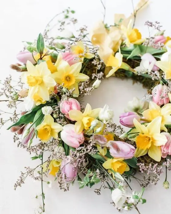 a beautiful spring wreath completely covered with spring blooms like daffodils, tulips and some blooming branches