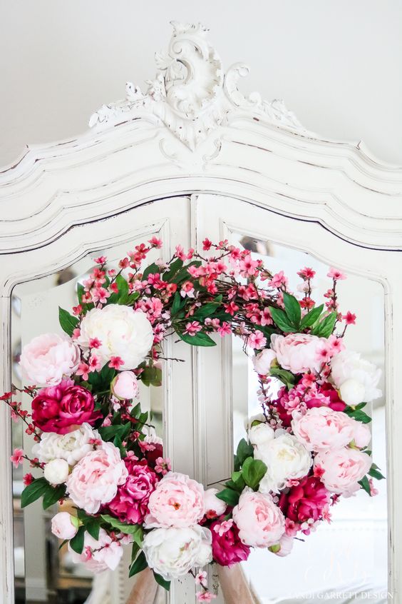 a bright spring wreath of faux flowers in white, blush and hot pink and blooming branches is a great idea for the season