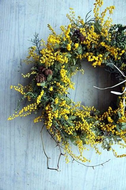 A bright spring wreath with greenery, mimosa, pinecones and twigs is a very cool and eye catchy solution