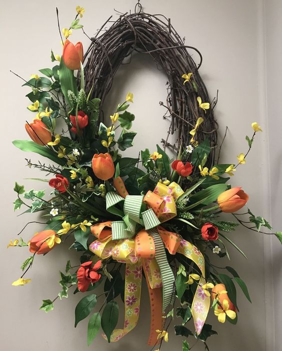 a brigth spring wreath of vine, bright orange and red tulips, twigs, greenery and blooming branches plus bold bows