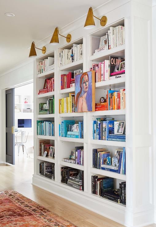 a built-in bookshelves with colorful books and brass wall lamps are great for any space