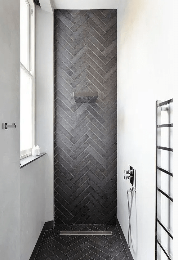 a chic contemporary shower space with white walls and an accent graphite grey skinny tiles clad in a chevron pattern and extended to the floor