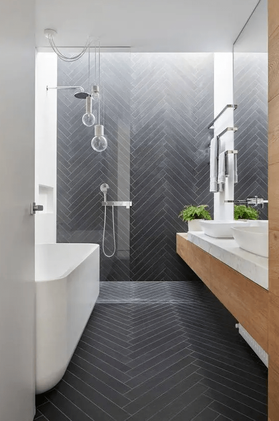 a contemporary bathroom clad with long and skinny graphite grey tiles in a chevron pattern
