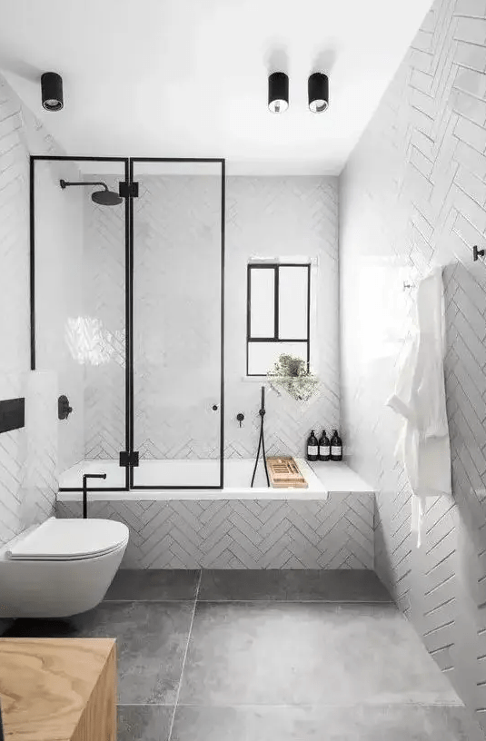 a contemporary bathroom with glossy white tiles, large scale tiles on the floor, black fixtures and a window for more light