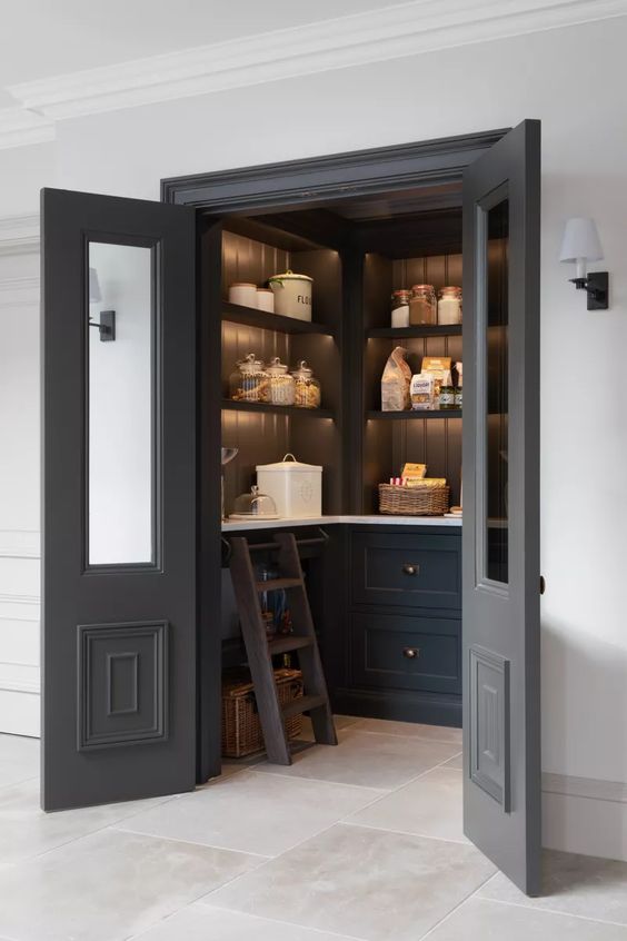 a cool dark pantry with doors, built in cabinetry and shelves with lights plus a ladder is lovely for a farmhouse space