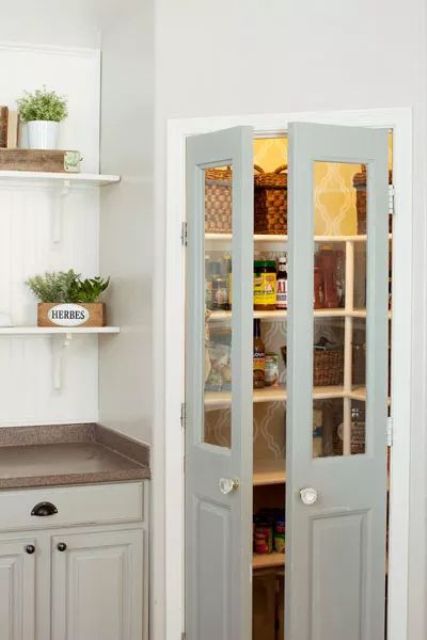 a corner pantry with light grey doors, lights and built-in open shelving is a cool space for storage
