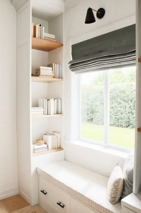 A cozy windowseat with built in bookshelves on both sides and a grey curtain is a stylish space