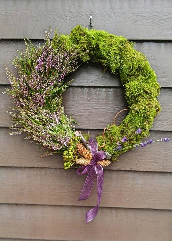 a creative spring wreath with moss and blooming branches, pinecones and a purple bow is a cool solution for spring