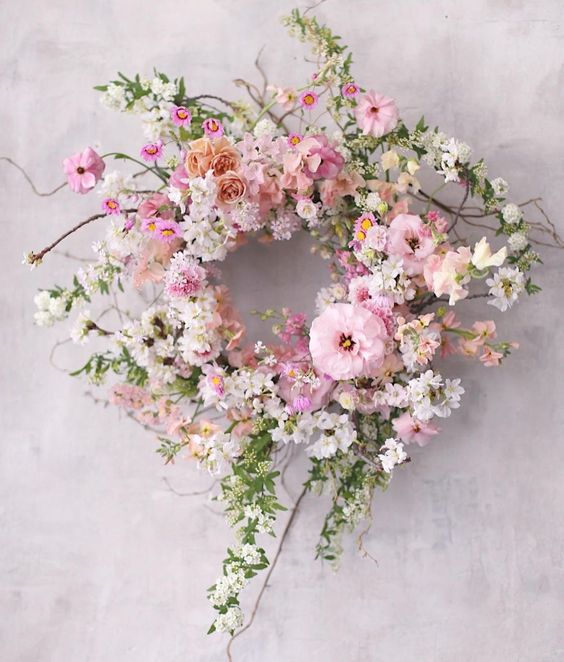 a gorgeous messy spring wreath completely done with pink, blush and white blooms, twigs and branches is wow