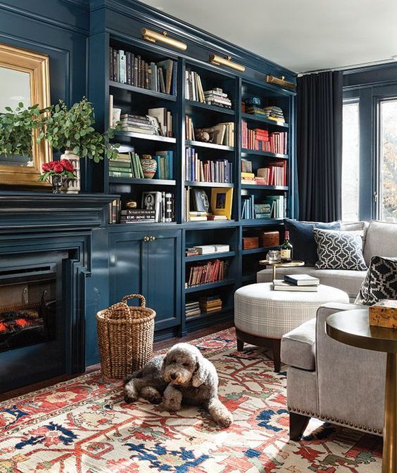 A navy living room with built in shelves, a built in fireplace, neutral furniture and a printed pillows, a printed rug