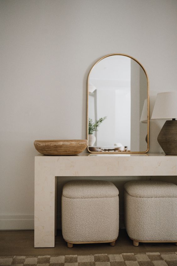 a neutral console table, neutral boucle poufs, a bowl, a mirror and a lamp for a serene contemporary entryway