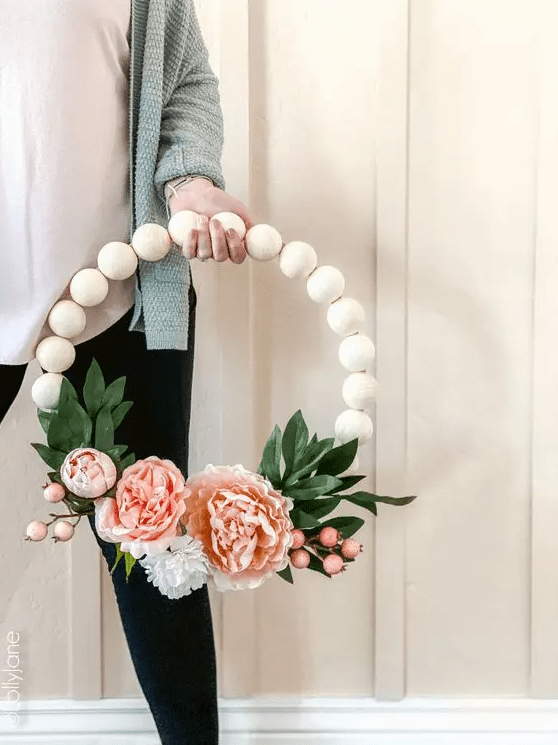 A pretty spring wreath of large wooden beads, pink blooms and berries and faux leaves is a simple and long lasting decoration
