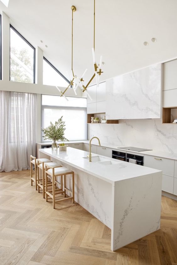 a refined and luxurious white marble kitchen with a herringbone floor that adds warmth and coziness to the space