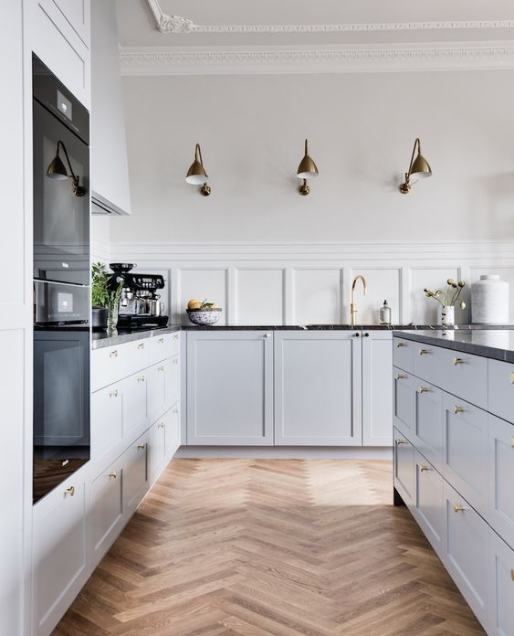 a serene Scandinavian kitchen with molding, a herringbone floor, dove grey lower cabinets and black stone countertops