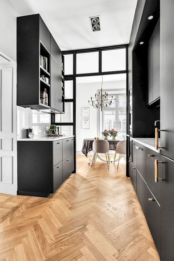 a small black galley kitchen with a herringbone floor that adds texture, interest and contrasts the black cabinetry