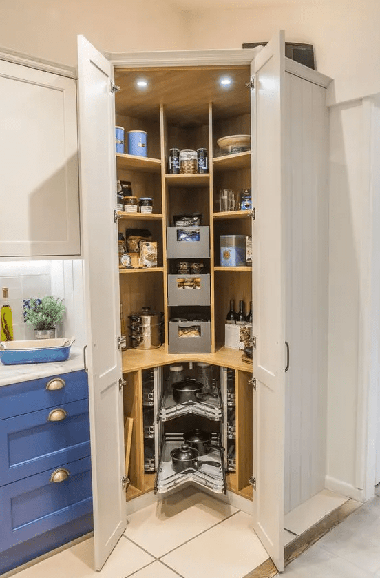 a small corner pantry with open shelves, drawers, built in lights, cookware and food, some wine bottles
