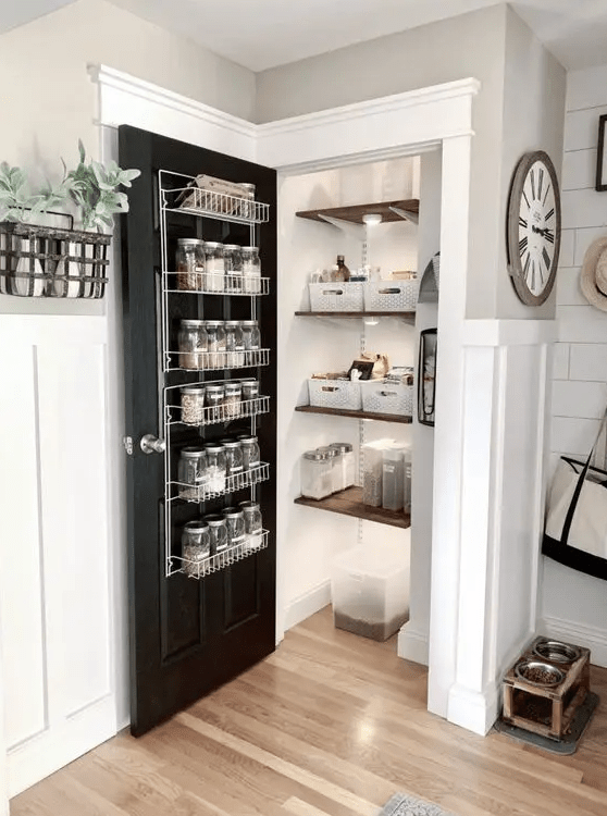 a small farmhouse pantry with shelves, lights, cubbies, a door with a metal shelving unit and spices on it