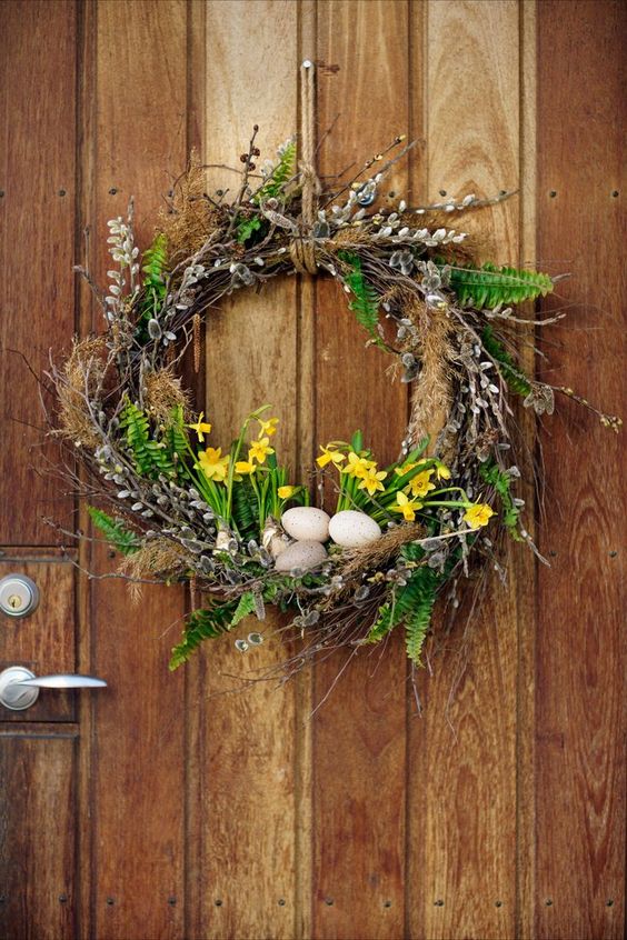 a spring wreath of vine, willow, blooms, greenery and some eggs with a strong Eater feel
