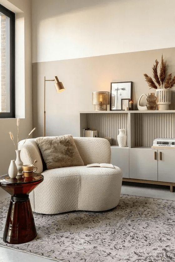 a stylish and refined nook with a neutral storage unit, a white boucle chair, a glass side table and some chic decor